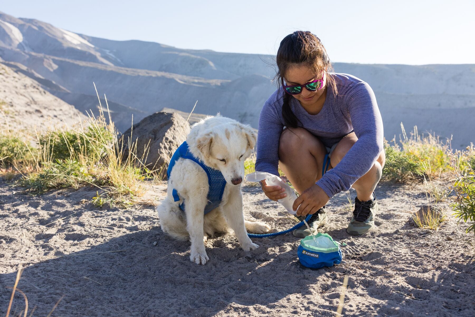 Woman pouring water into a bowl for her dog on the trail