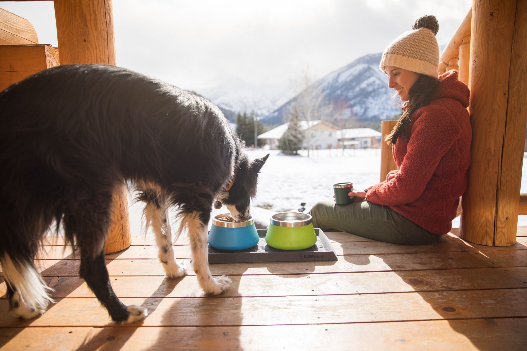Dog eats out of basecamp bowls on the porch of a cabin.