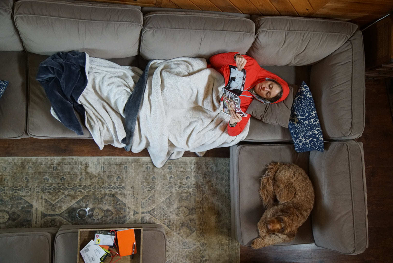 A woman and her dog rest on the couch. 