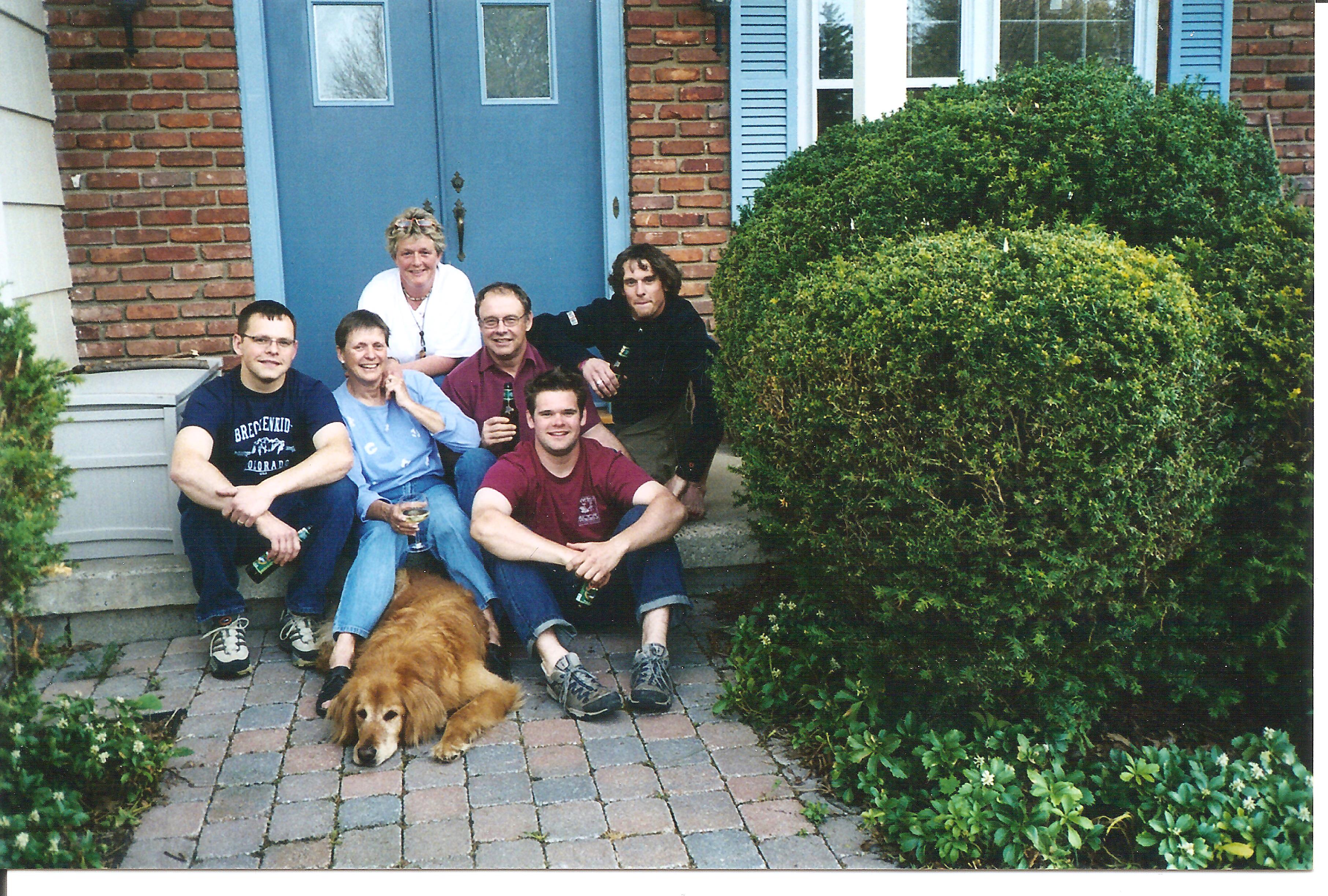 Timothy and his family with their dog on the porch steps.