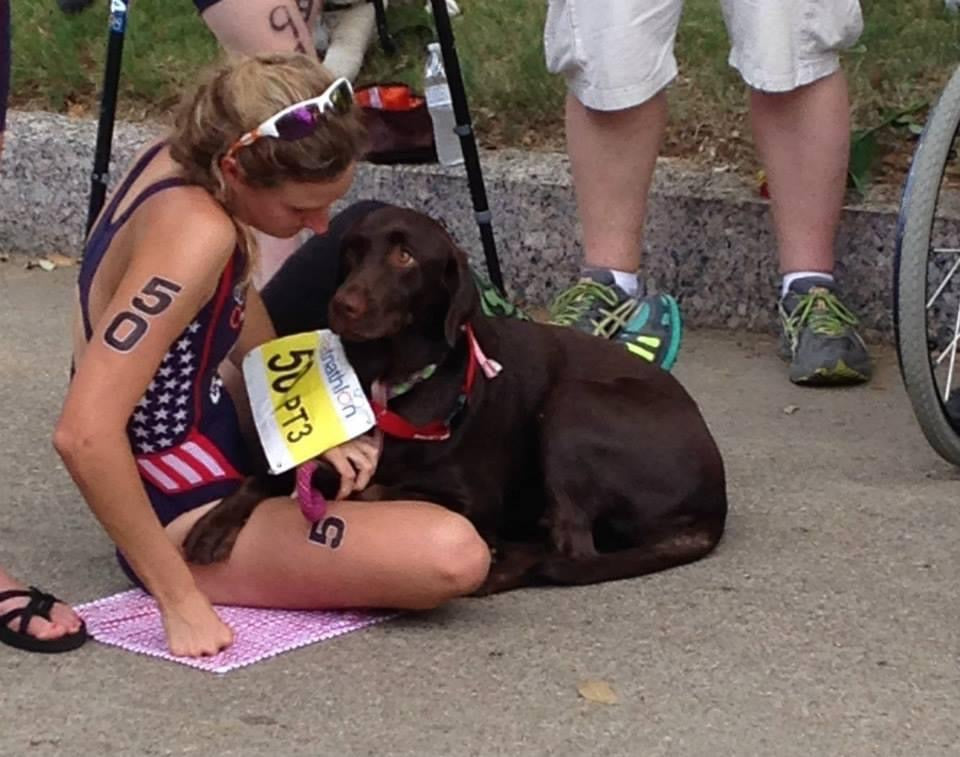 A triathlete sits with her service dog during a break in a race. 