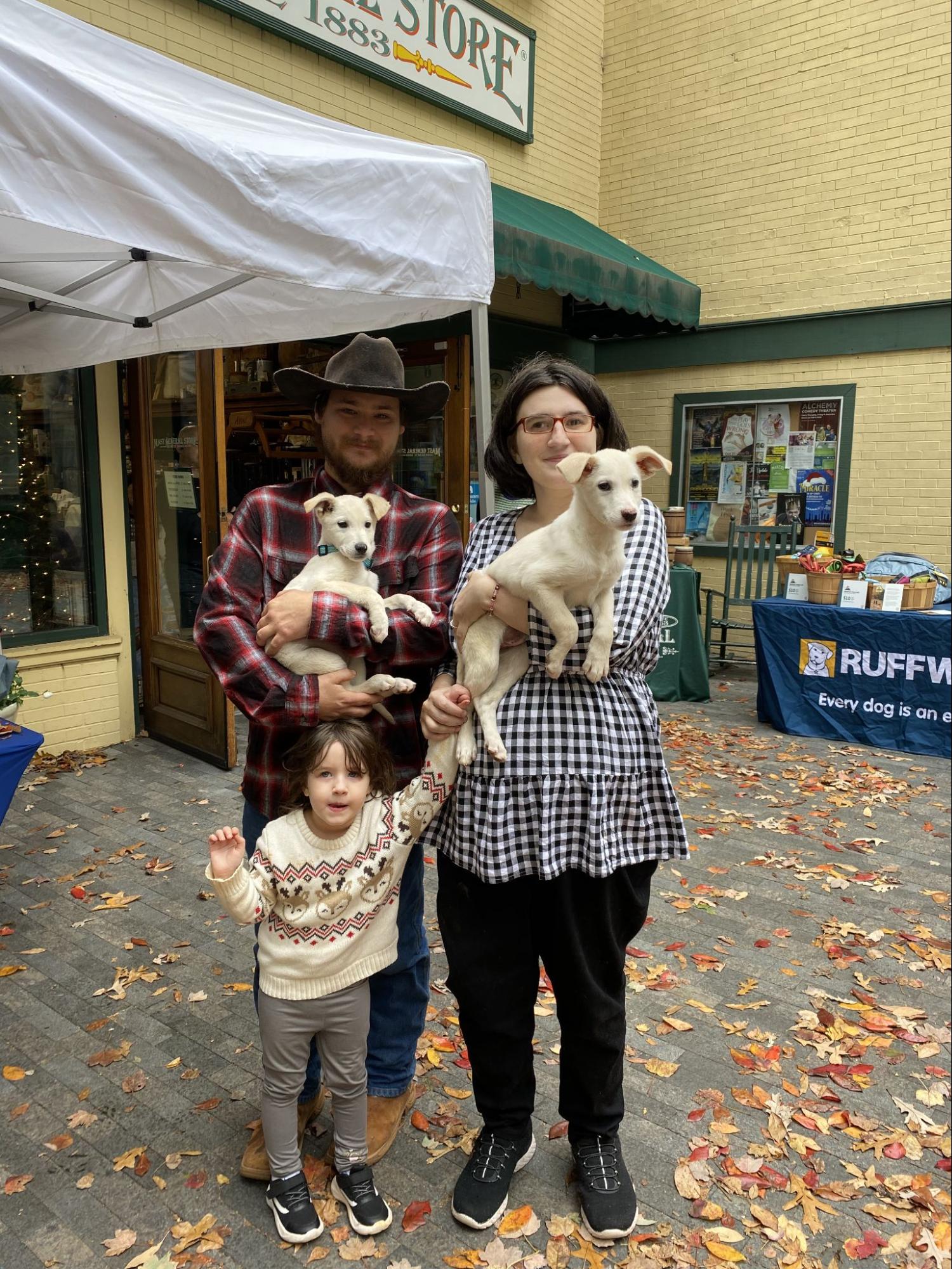 A man, woman, and their small child hold two puppies that they just adopted at the RAD event. 