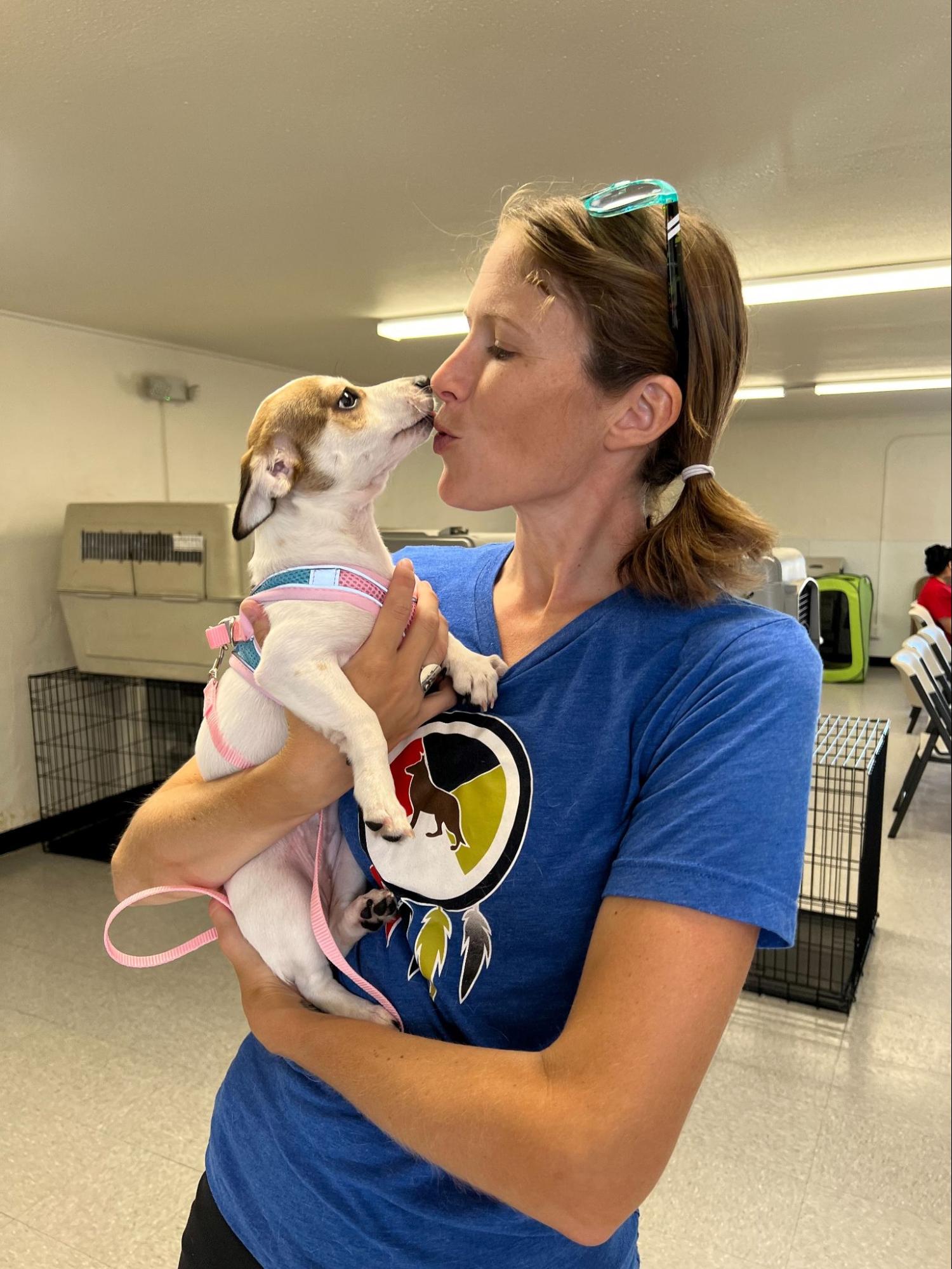 Woman holding and kissing a dog at an animal shelter