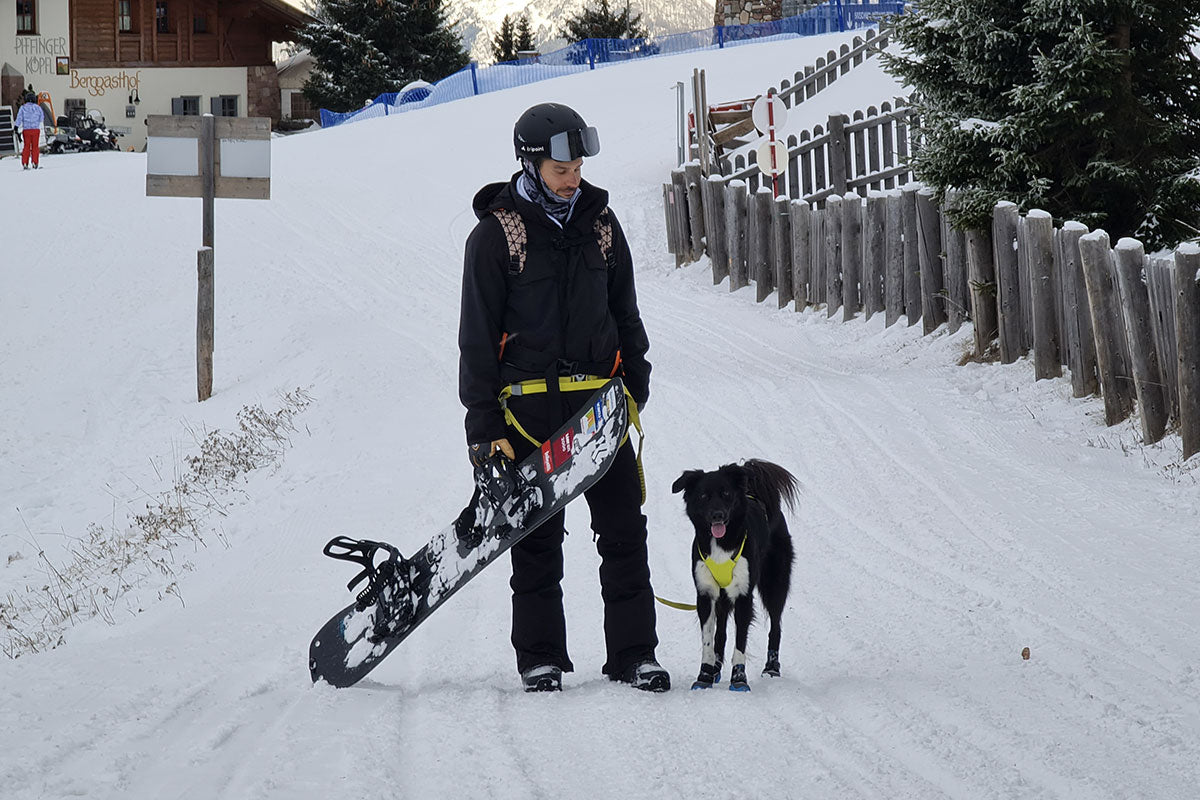 Omar and dog, Baku, stand at the end of a snowboarding run.