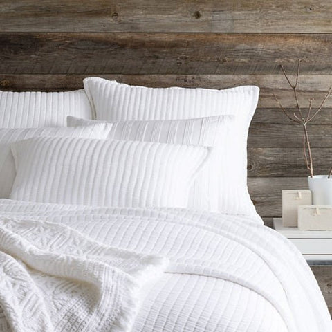 white matelasse coverlet on bed in room with wood plank walls