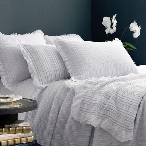 white matelasse coverlet with gray stripes on bed with pillows