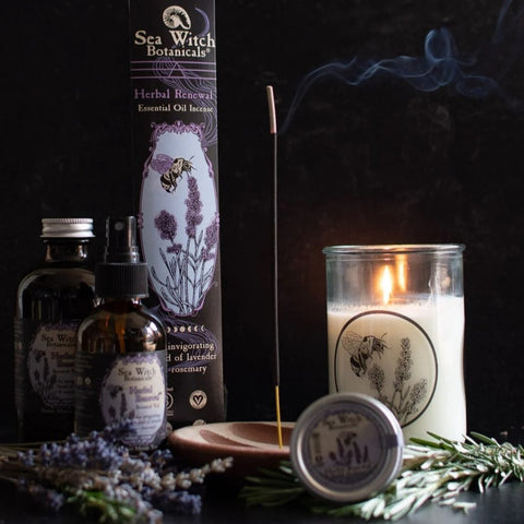 Herbal Renewal gift set with incense, spray, solid perfume, and candle, pictured with fresh lavender and rosemary, incense and candle burning.