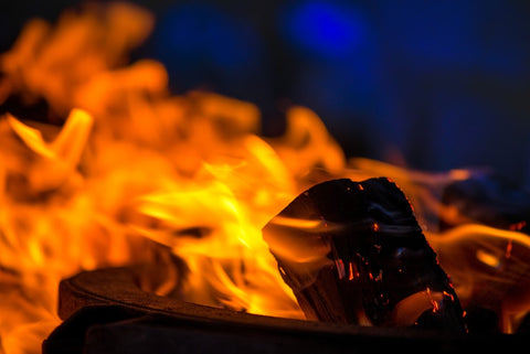 A macro shot of firewood, white dust and hot, glowing coal. Burning branches and wood.