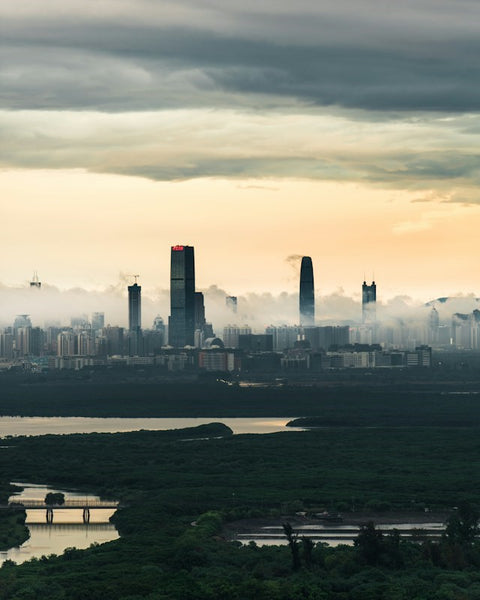 city skyline under clouds during twilight with a body of water