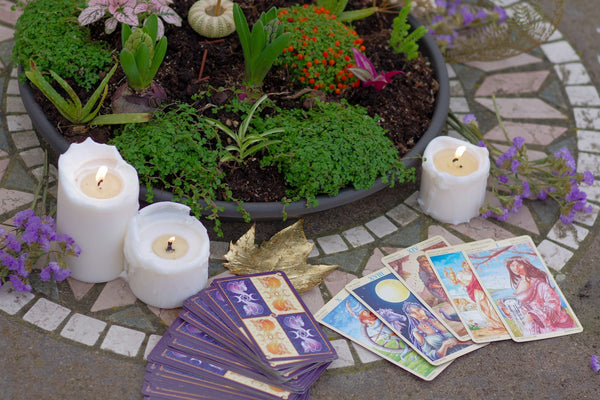 a table topped with candles and cards next to a potted plant.