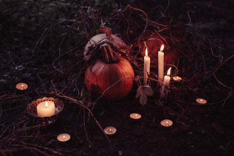 pumpkin with skull and candles in lowlit dry grass