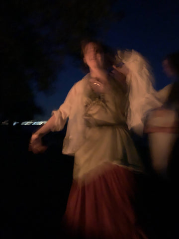Blurry, person dancing by firelight in the dark