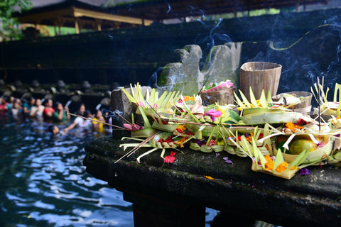 burning incense, candles, and plants on a table over water