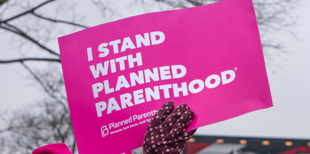 Pink sign that reads "I STAND WITH PLANNED PARENTHOOD" Unidentified particpants at the 2017 Women's March Minnesota. The Women's March represented the worldwide protest to protect women's rights and other causes.