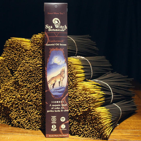 Package of Timberwolf Incense leaning against bundles of the sticks on wooden table with dark background.
