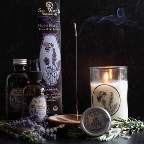 Herbal Renewal gift set with incense, spray, solid perfume, and candle, pictured with fresh lavender and rosemary, incense and candle burning.