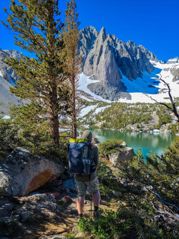 A hiker standing in some trees by a lake