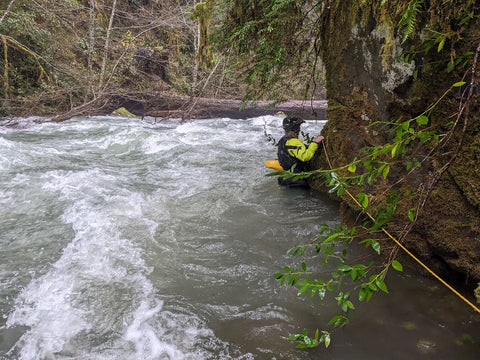 Rafter hanging on to the edge of the creek in the water