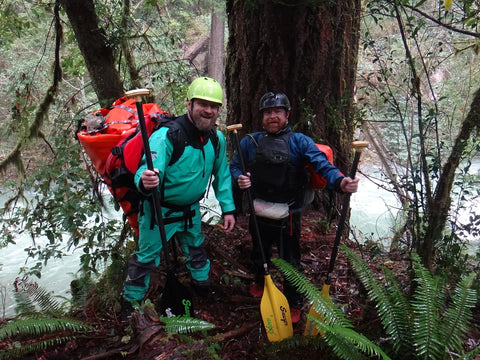 two rafters down by the river carrying boats