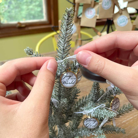 Adding an advent ornament to a miniature tree.