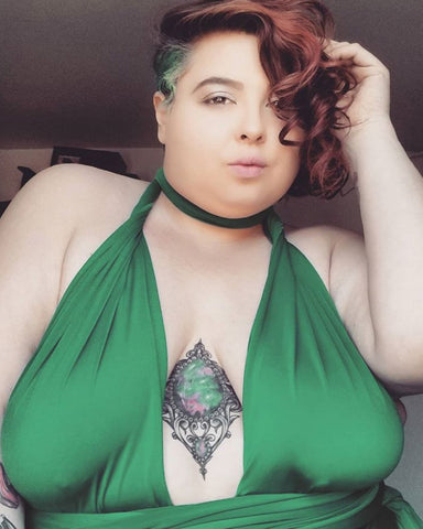 Image of Jewelz Mazzei from her Instagram account @jewelzjourney, plus-size model with sternum tattoo and Henkaa Emerald Green Sakura infinity dress looks at the camera.