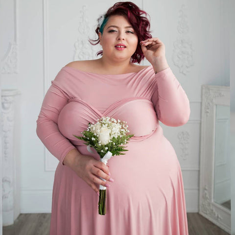 Plus-size model Jewelz Mazzei in wears a Henkaa Dusty Rose Iris Midi convertible dress and looks into the camera.