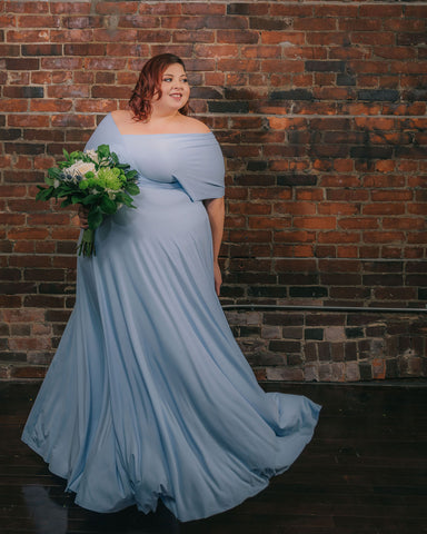 Plus-model @jewelzjourney wearing a Henkaa Light Sky Blue Sakura Maxi infinity dress and holding a bouquet of flowers.