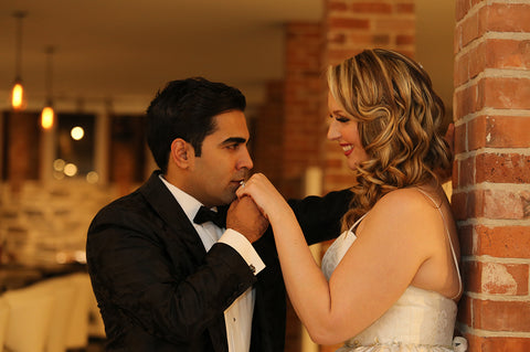 Subhir Uppal kisses Stephanie Rochefort's hand during their portrait session for their multicultural wedding.