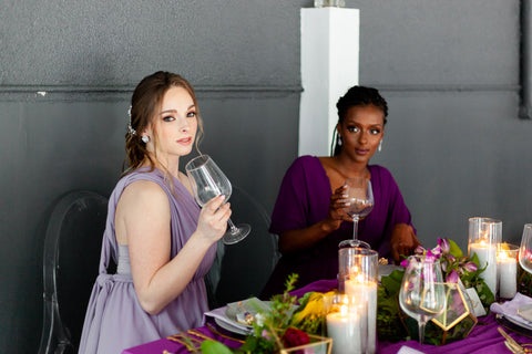 Two models wearing the Dusty Purple and Plum Purple Daffodil Chiffon Convertible Dress as bridesmaids.
