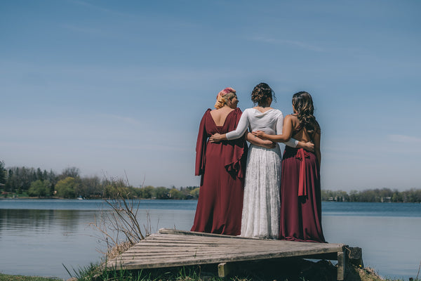 Three women standing on a dock wearing Henkaa Burgundy Wine Daffodil Chiffon, Sakura Maxi, Iris Maxi and Iris Lace convertible wedding wedding dress.