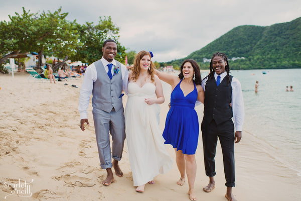 Wedding party walks together on white-sand beach in Saint Lucia wearing Henkaa wedding dress, bridesmaid dress and ties.