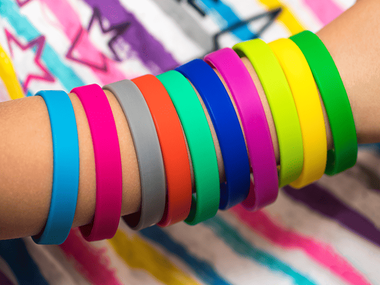 Rubber wristbands of all colors on a persons arm