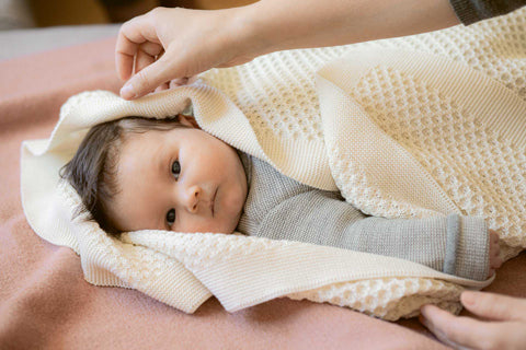 Disana honeycomb organic merino wool baby blanket natural wrapped around a baby