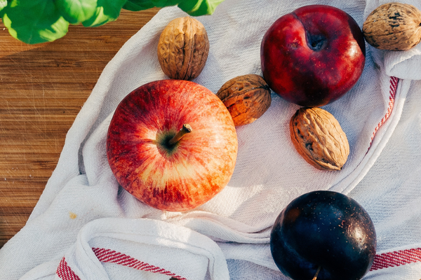 Apples and nuts and a plum on a tea towel.