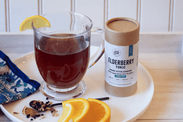 Elderberry Tonic tea in clear mug with orange slices.