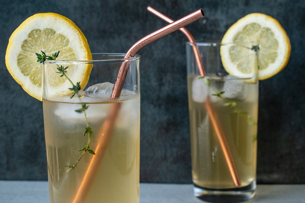 two glasses of iced green tea with lemon and rosemary with copper straws