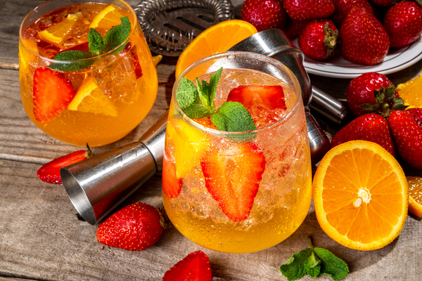 strawberry and orange tea mocktail with fresh strawberries and halved oranges