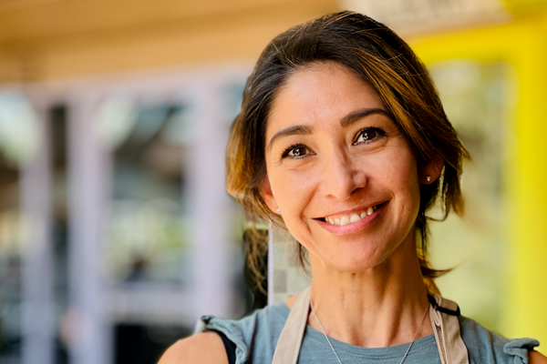 Woman smiling standing outside of a store.