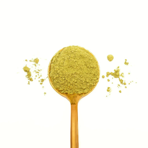 ceremonial grade matcha on a gold spoon with white background