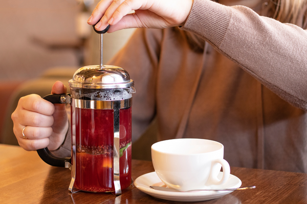 person using french press for tea