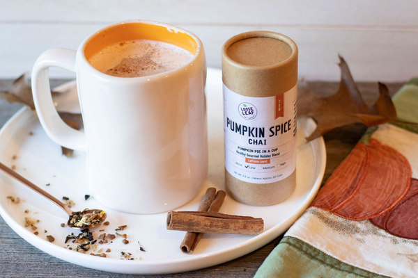 A cup of Pumpkin Spice Chai latte next to a canister of Pumpkin Spice Chai tea.