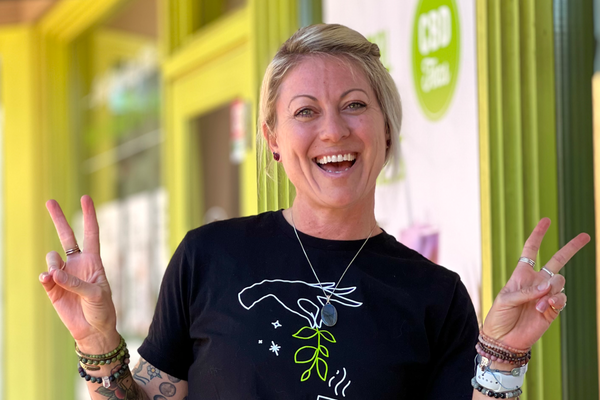 Happy woman standing outside of a shop with green trim.