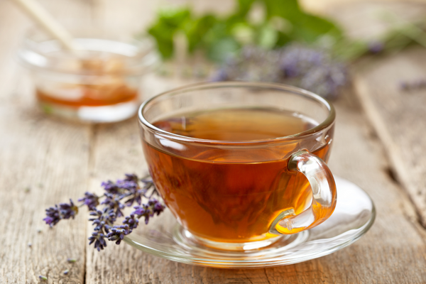 lavender herbal tea blend for sleep dark brewed in a glass cup with fresh lavender on the side