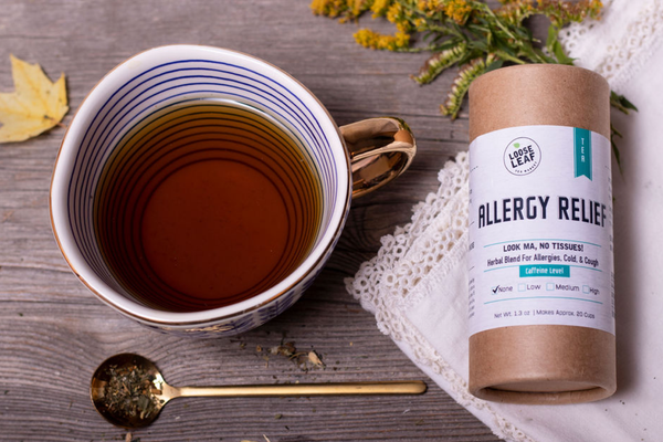 Allergy Relief tea in mug, with gold spoon on wooden board.