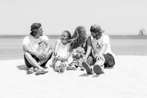family of 4 sitting on a beach