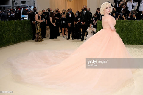 Billie Eilish in a large dramatic nude pink old fashion ball gown. She is wearing classic makeup and a long shag haircut 