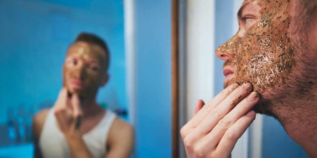 Man exfoliating in front of a mirror