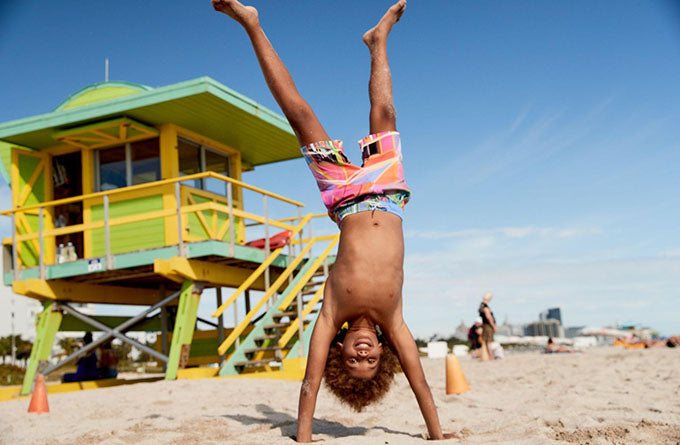 boy doing hand stand on beach