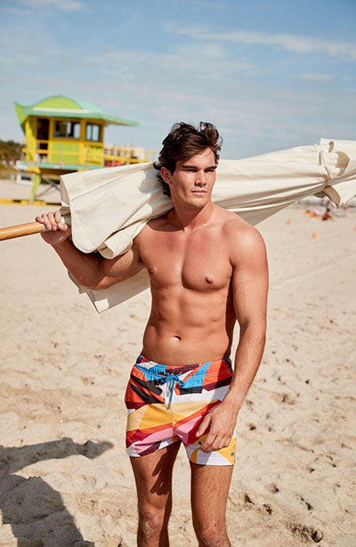 man in stylish swim trunks on beach