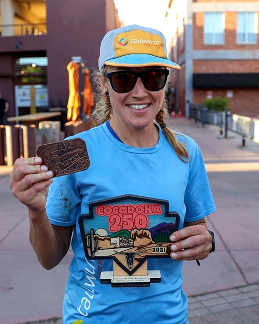 Maggie Guterl holding buckle and first place trophy for Aravaipa Cocodona 250 Ultramarathon